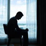 Home Page sad man sitting in the dark room.