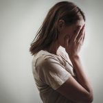 Home Page portrait of depressed woman, covering face with her hands, side view